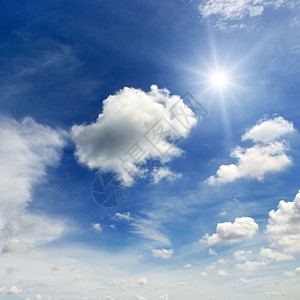 明亮的阳光和云彩笼罩在一片深蓝的天空中图片