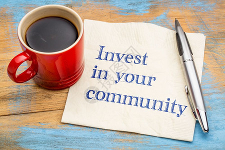 在你的社区投资笔迹在餐巾纸上加一杯咖啡背景图片