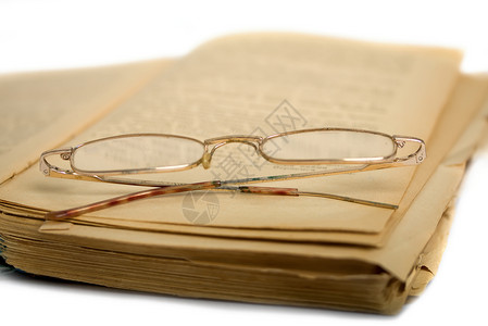 旧的破书和阅读眼镜躺在书上图片