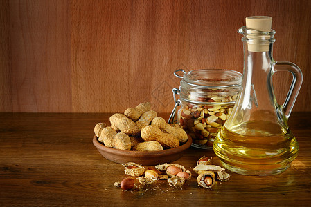带壳花生木制桌上瓶装花生油和干坚果中的花生油背景