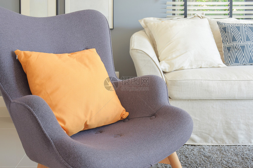 在客厅的回旋式扶椅上橙色枕头图片