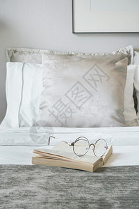 在床上用天鹅绒玻璃和书天鹅绒在背景上完成枕头图片