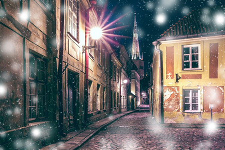 圣让浸信会爱沙尼亚塔林市中世纪老城和圣奥拉夫浸信会冬季寒夜的圣奥拉夫浸信教堂的狭窄街道照亮爱沙尼亚塔林旧城夜街背景