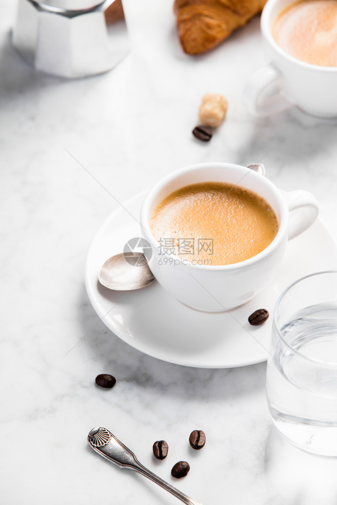 白大理石背景的咖啡成分含水和羊角面包的白色杯子中咖啡浓缩图片