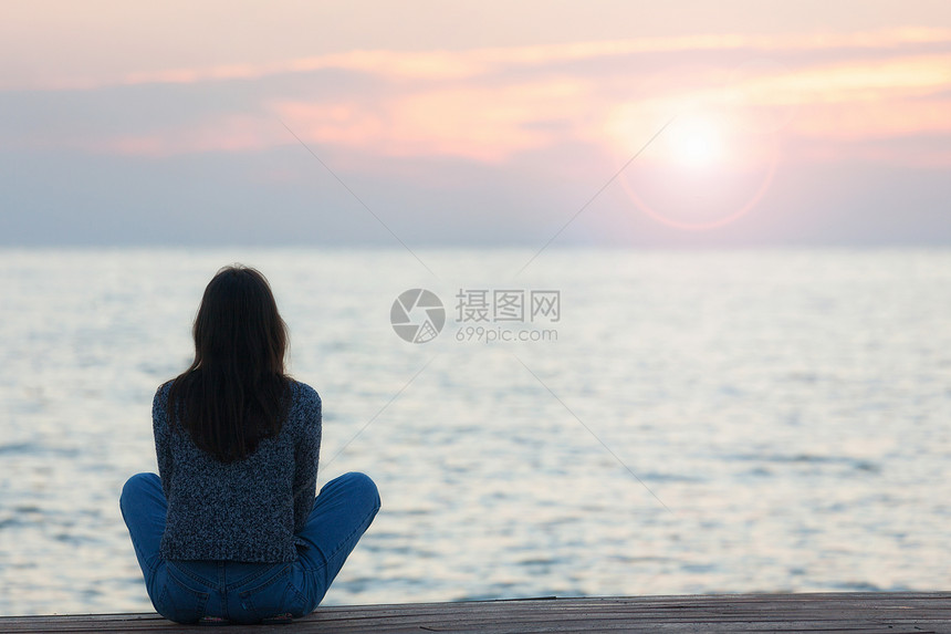 一个女人在日落时海滩观晒太阳的轮光图图片
