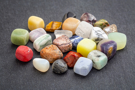 石块上有彩色宝一堆磨光的可贵多彩宝石与灰色块对立背景图片