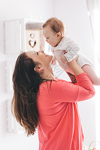 年轻女把她的婴抱起养育子女的概念抚养孩子图片