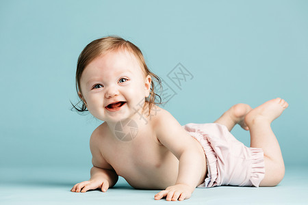快乐的小孩在蓝背景的地上爬可爱婴儿快乐小孩在地上爬高清图片