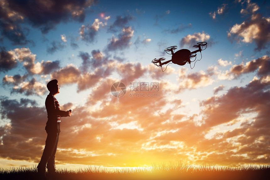 日落时一名男子操作无人机空中摄像工作图片