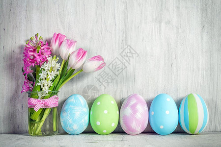 复活节鸡蛋和木制桌边的春花束装饰复活节鸡蛋和木制桌边的春花束图片