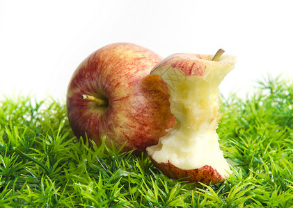 部分被咬的苹果躺在绿草上图片