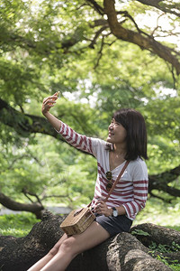 女人在公园里拍个自带智能手机到户外背景图片