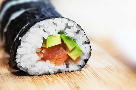 日本人亚洲健康食品鲑鱼寿司鳄梨海藻大米和木桌上的筷子图片