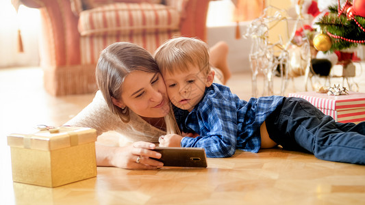 母亲和金发小孩躺在地上看手机背景图片
