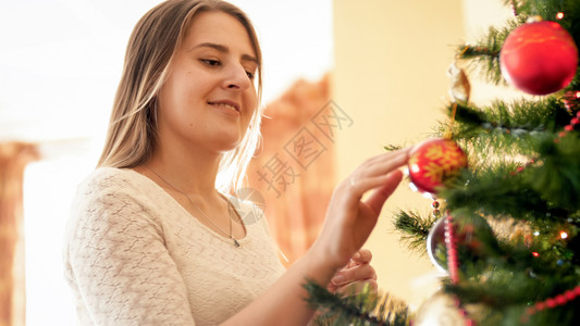 站在美丽的圣诞树旁快乐微笑年轻女人肖像图片