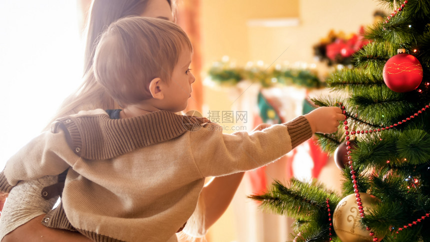 可爱的小男孩在克里斯马塔树上装饰可爱的小男孩在克里斯马塔树上装饰的近镜头照片图片