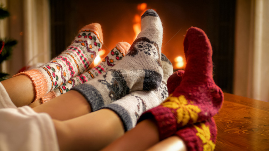 家庭在起居室燃烧的壁炉上暖脚照片图片