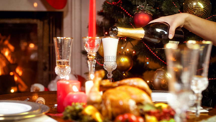 在家庭圣诞晚宴上装满瓶香槟的杯子贴近照片图片