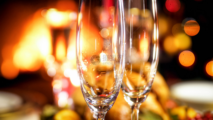 空香槟杯对着燃烧的壁炉和明亮圣诞树紧贴照片空香槟杯对着燃烧的壁炉和明亮圣诞树紧贴图像图片