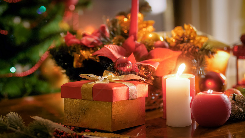 在客厅的圣诞树对着烧蜡烛和带金丝的礼品盒和在客厅的圣诞树对着烧蜡烛的紧贴照片图片