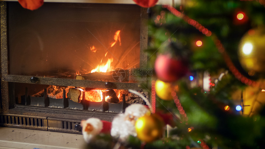 在圣诞树旁边的客厅燃烧壁炉在装饰圣诞树的旁边客厅燃烧壁炉图片