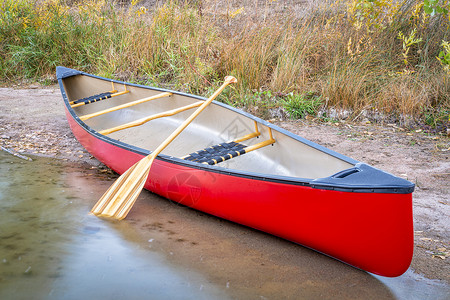 在湖岸上用木板划桨的红色独木舟背景图片