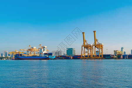进出口企业的集装箱货船和城市的物流国际货中午和蓝天用起重机将货物运往港口背景图片