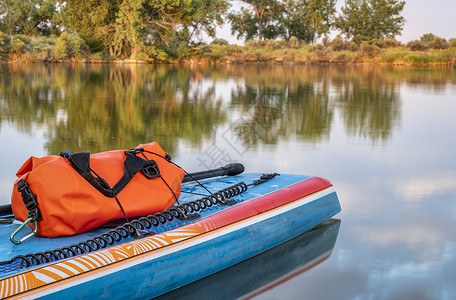 在科罗拉多北部的平静湖岸上夏季风景中用桨安全皮带和防水护身衣站起桨板在夏季风景中划桨安全带和防水护身衣背景图片