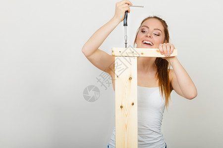 妇女用螺丝起子组装木家具背景图片