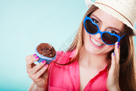 戴蓝帽子的女孩欢乐的夏天时装女人穿着草帽心戴墨镜的手持蓝底蛋糕背景