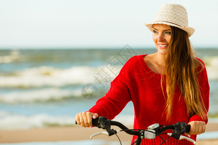 女孩躺着海滩在海边骑自行车的年轻活跃女孩夏天在海上附近躺着笑的可爱女人时装旅游者在新鲜空气中时装女孩在户外骑自行车背景