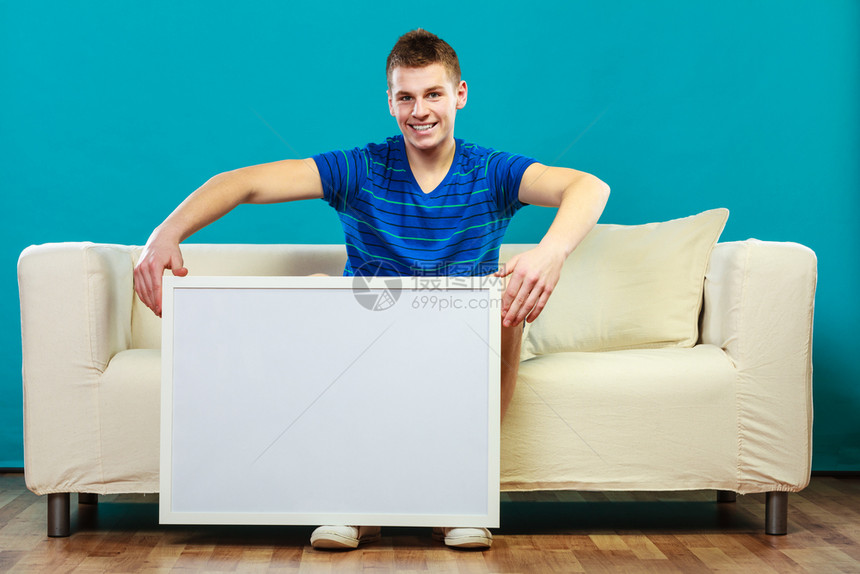 广告概念年轻人坐在沙发上用空白的演示文稿板男模型显示横幅标志广告牌复制蓝色文本的空间图片