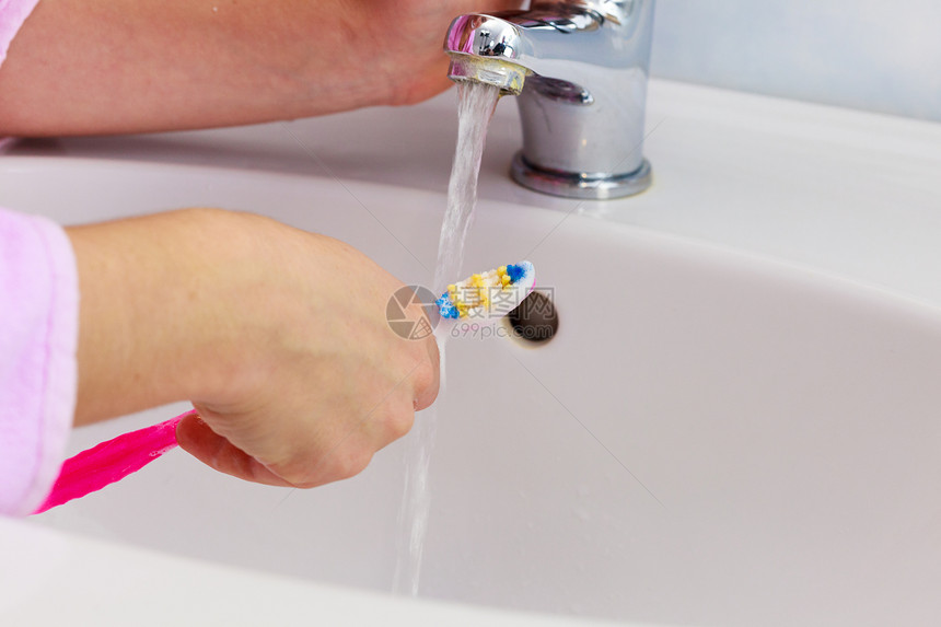 妇女手持牙刷和膏在洗手间水槽和背景龙头中手持牙刷在洗间图片