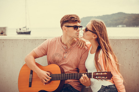 女友亲吻在海岸边弹吉他的男友图片