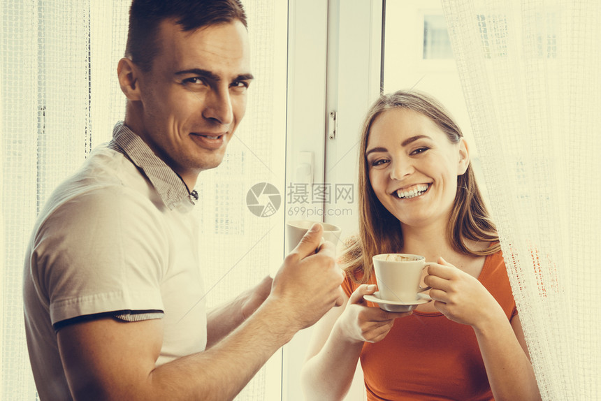有吸引力的情侣在家中一起喝茶或咖啡男人和女在家中端杯子和热饮图片