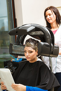 m型脱发头发放松和型概念坐在黑披风上的女人在机器下脱发背景