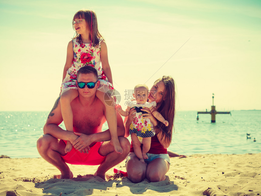 快乐的家庭在海滩上玩家庭在海边滩上摆姿势图片