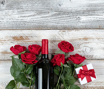 以红酒和礼物在白锈木材底部庆祝浪漫情人节图片