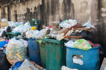 在泰国曼谷市城一堵墙附近存放各种类型的大垃圾堆塑料袋和垃圾桶采用环境污染概念背景图片