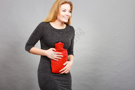 胃痛期和月经抽筋问题概念有胃抽筋的妇女对用热水瓶喝感到宽慰图片