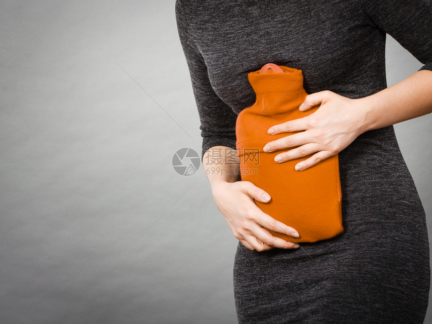 胃痛期和月经抽筋问题概念有腹部抽筋的妇女拿着热水瓶感觉非常不舒服妇女拿着热水瓶感到胃部抽筋图片
