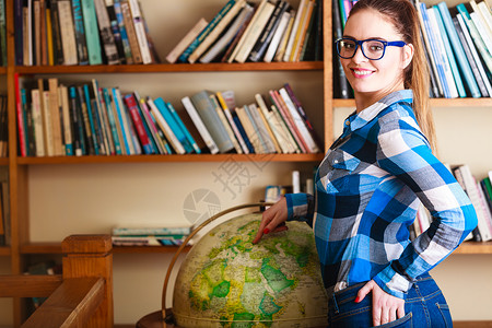教育旅行和地理概念年轻可爱的女学生在图书馆的蓝眼镜女学生指向全球图片