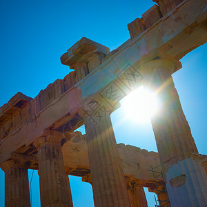 阳光穿透希腊雅典一座寺庙的古老柱子背景图片