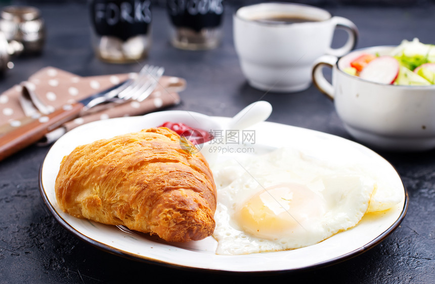 餐桌上的早炒鸡蛋和羊角面包图片