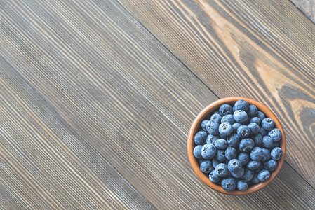 木制桌上的蓝莓碗图片