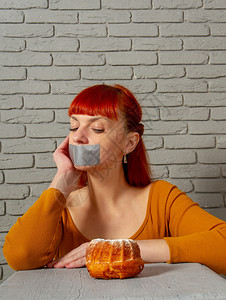 一位年轻红头发女孩的概念形象坐在饮食中与她的嘴边背景高清图片素材