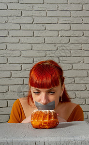 一位年轻红头发女孩的概念形象坐在饮食中与她的嘴边银高清图片素材