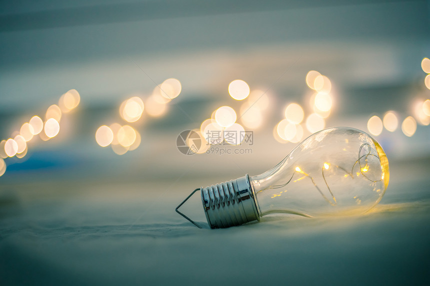 LED灯泡躺在床上是思想和创新的标志是模糊背景中的亮光图片