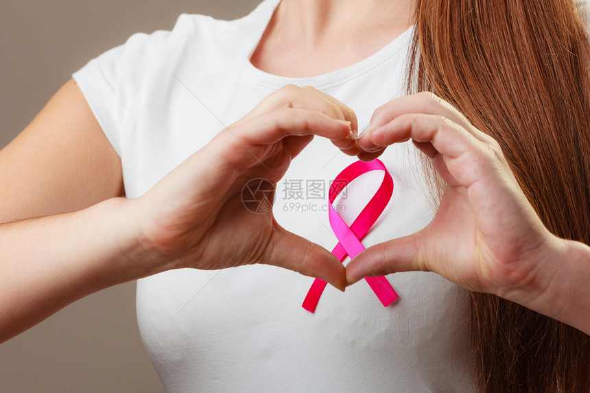 关紧女手会把心放在粉色丝带符号上帮助和慈善乳腺癌女人的手会把心放在粉色丝带上图片