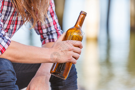 人在户外海滩上喝着酒瓶子;人和酗酒问题;人渣和酗酒问题;人渣和瓶子在海滩上喝着酒瓶子背景图片
